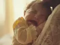 Malutkie dziecko płacze, tulone przez mamę. Ząbkowanie i biegunka to trudny czas dla malucha.