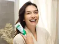 Uśmiechnięta kobieta trzymająca pastę GUM Original White. Dbanie o dziąsła (gum care) to klucz do pięknego uśmiechu.