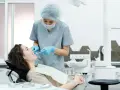 Dentystka bada zęby pacjentki, szukając oznak problemów, które mogą wymagać leczenia kieszonek dziąsłowych.