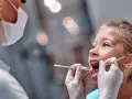 Mała dziewczynka u dentysty. Czas na kontrolę, kiedy wypadają trójki mleczne.