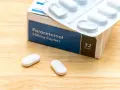 Opakowanie paracetamolu 500mg i dwie tabletki na drewnianym tle. Szybka ulga w bólu zęba.