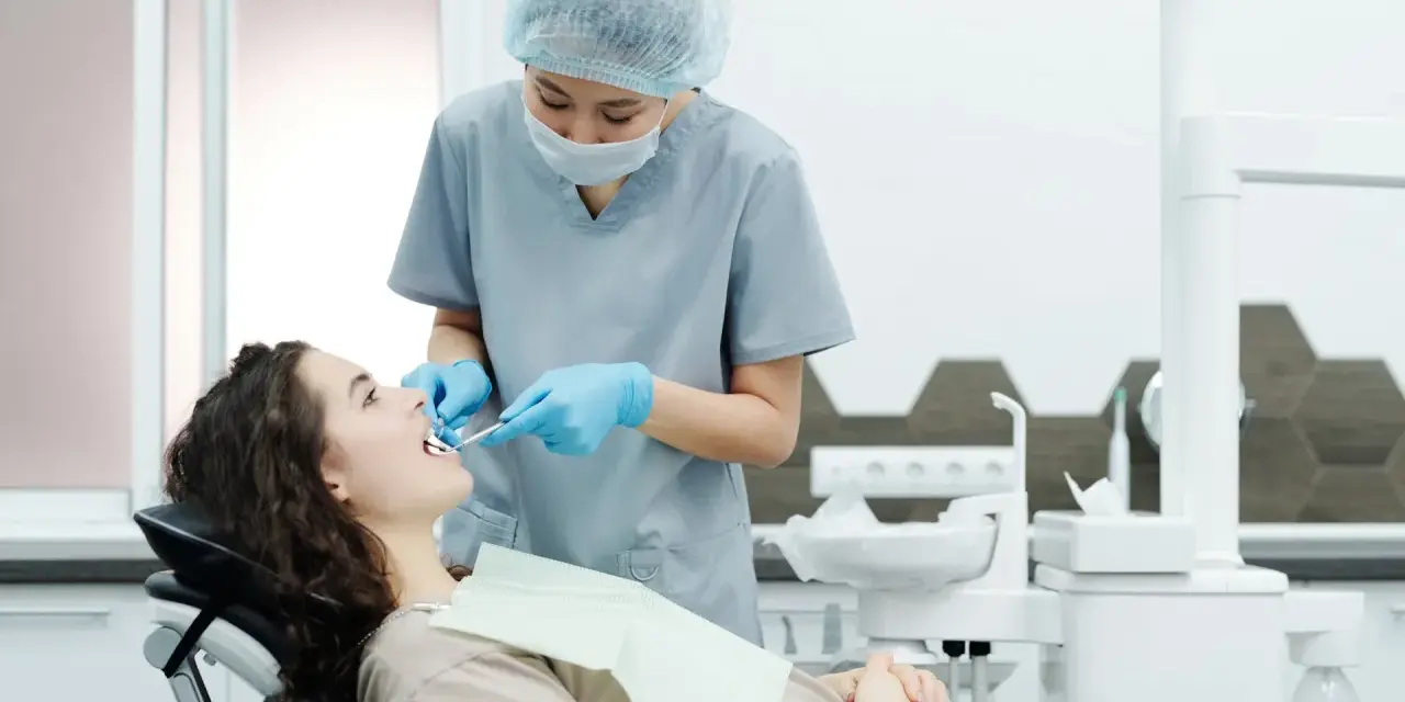 Dentystka bada zęby pacjentki, szukając oznak problemów, które mogą wymagać leczenia kieszonek dziąsłowych.