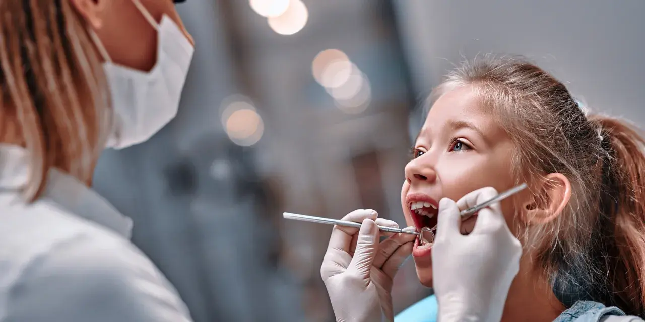 Mała dziewczynka u dentysty. Czas na kontrolę, kiedy wypadają trójki mleczne.