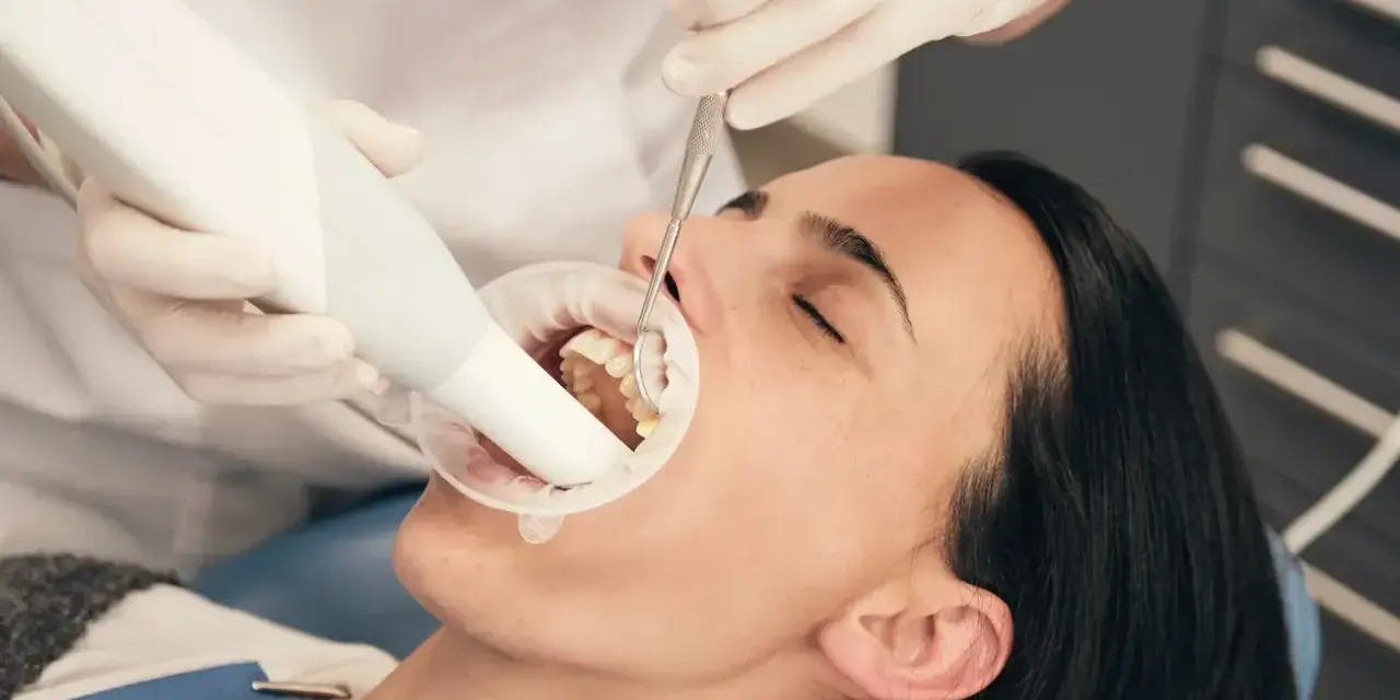 Dentysta bada zęby pacjentki, która używa specjalnej pasty na ruszające się zęby.