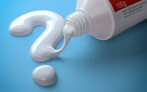 Biała pasta do szczoteczki sonicznej tworzy znak zapytania na niebieskim tle.
