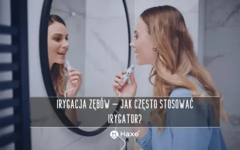 Kobieta używa irygatora do zębów przed lustrem. Dowiedz się, jak często stosować irygator dla zdrowego uśmiechu.