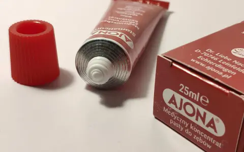 Pasta Ajona, medyczny koncentrat do zębów. Zastanawiasz się nad jej skutkami ubocznymi? Tubka i opakowanie na białym tle.