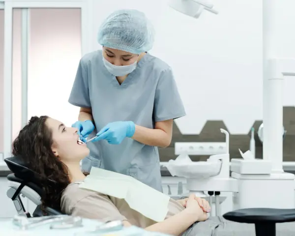 Dentystka bada zęby pacjentki, szukając oznak problemów, które mogą wymagać leczenia kieszonek dziąsłowych.