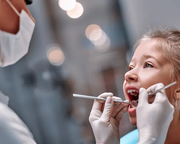 Mała dziewczynka u dentysty. Czas na kontrolę, kiedy wypadają trójki mleczne.