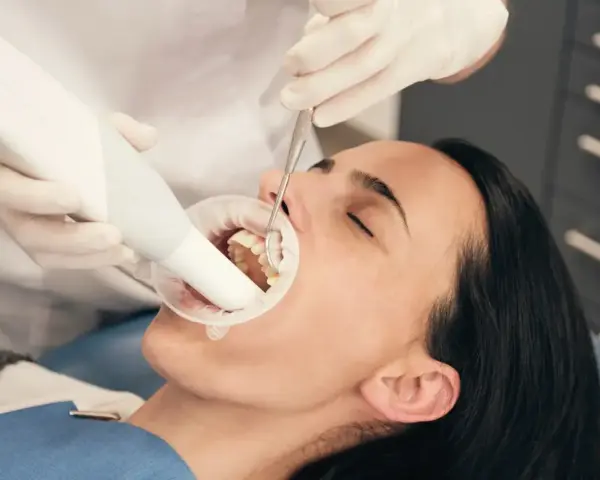 Dentysta bada zęby pacjentki, która używa specjalnej pasty na ruszające się zęby.