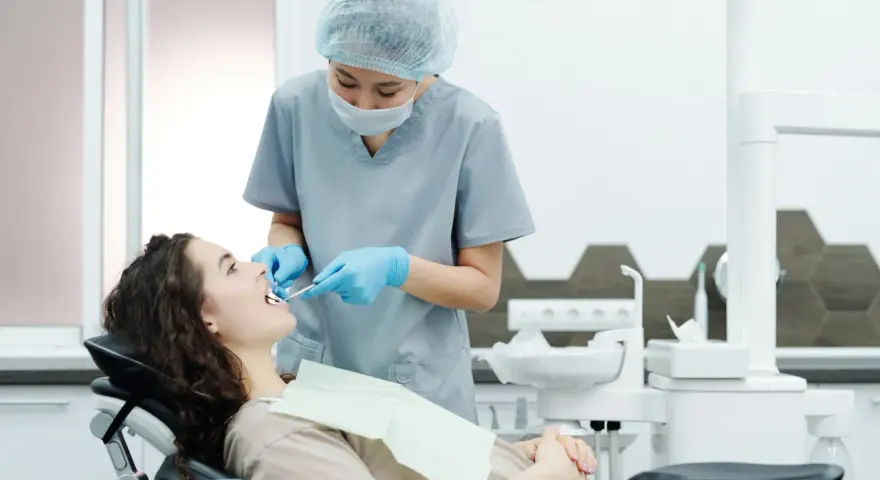 Dentystka bada zęby pacjentki, szukając oznak problemów, które mogą wymagać leczenia kieszonek dziąsłowych.