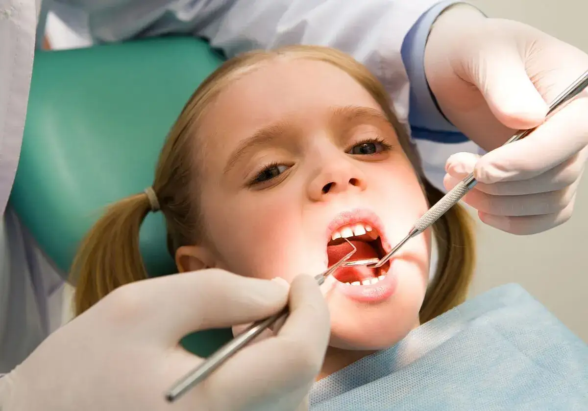 Mała dziewczynka ma badane siekacze u dentysty.