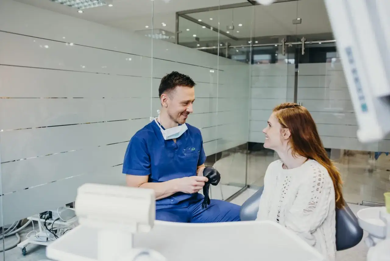 Dentysta w niebieskim uniformie rozmawia z pacjentką. Może właśnie opowiada o tym, jak pozbyć się bólu zęba na zimne.