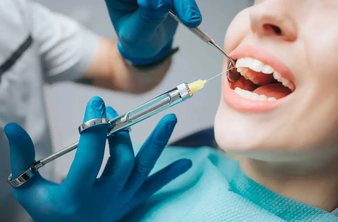 Dentysta podaje znieczulenie, by zapobiec drętwieniu dziąseł podczas zabiegu.